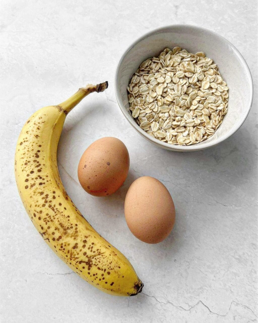 Ingredients for banana oat pancakes, including rolled oats, banana and eggs