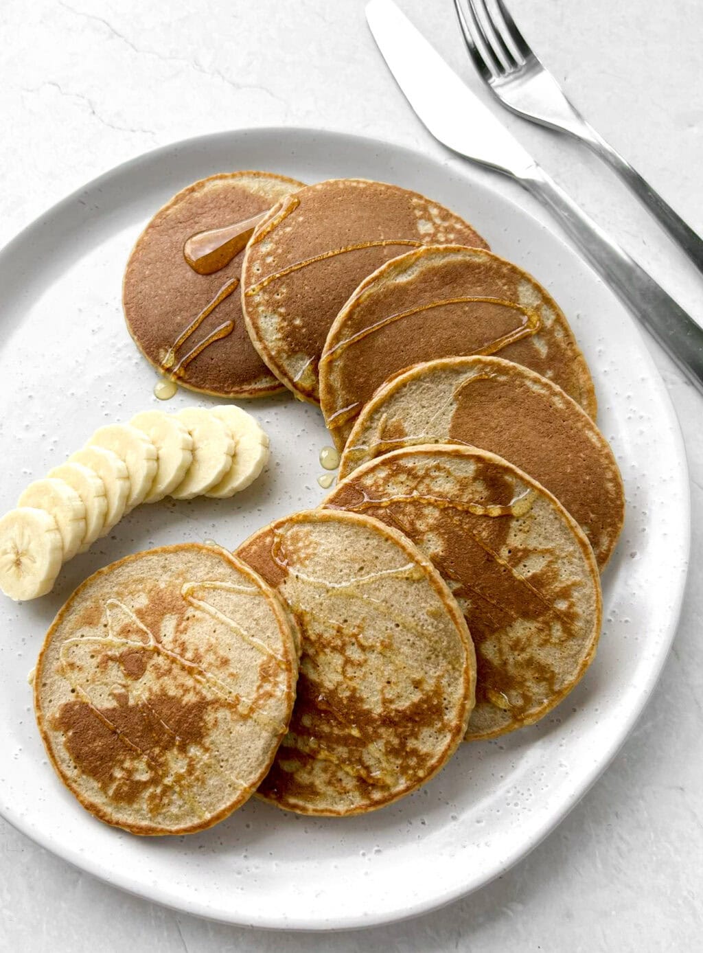 Banana oat pancakes on a serving plate with a drizzle of honey 