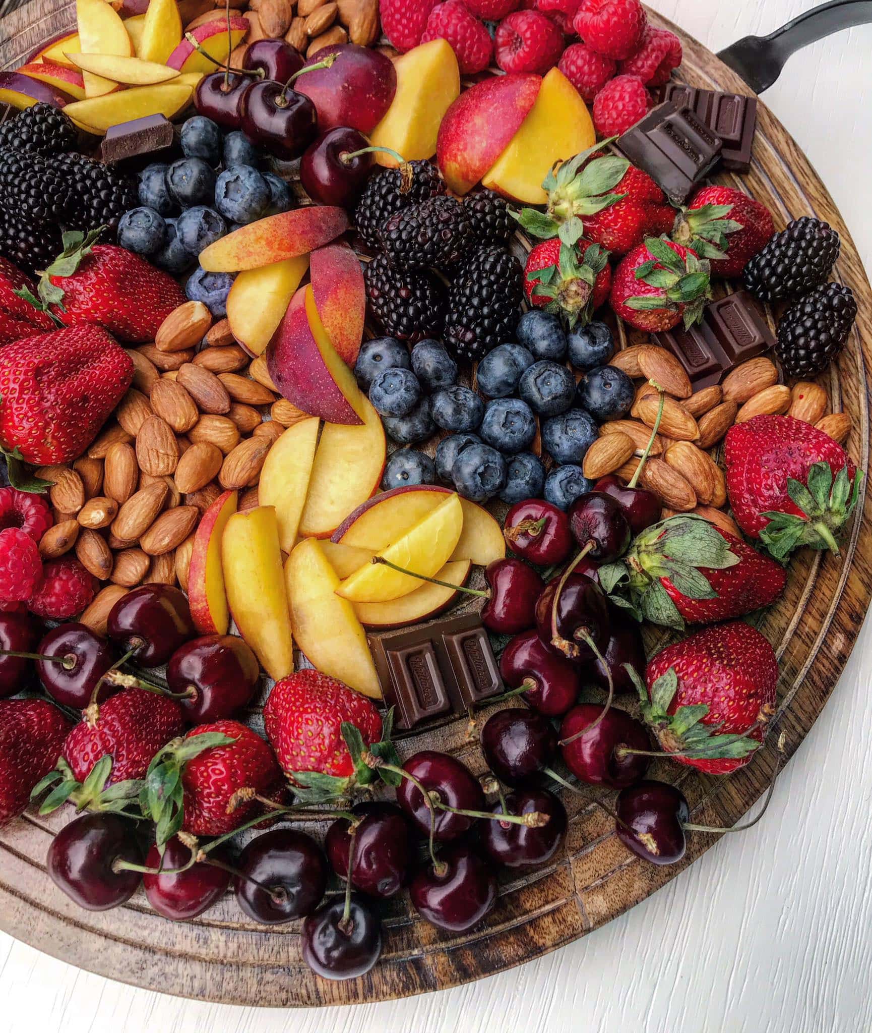 A grazing platter with summer fruit, dark chocolates and nuts