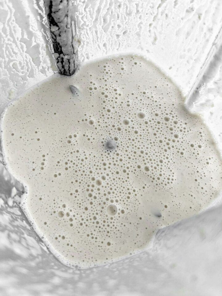 A food processor with cashews blended with water into cashew cream.