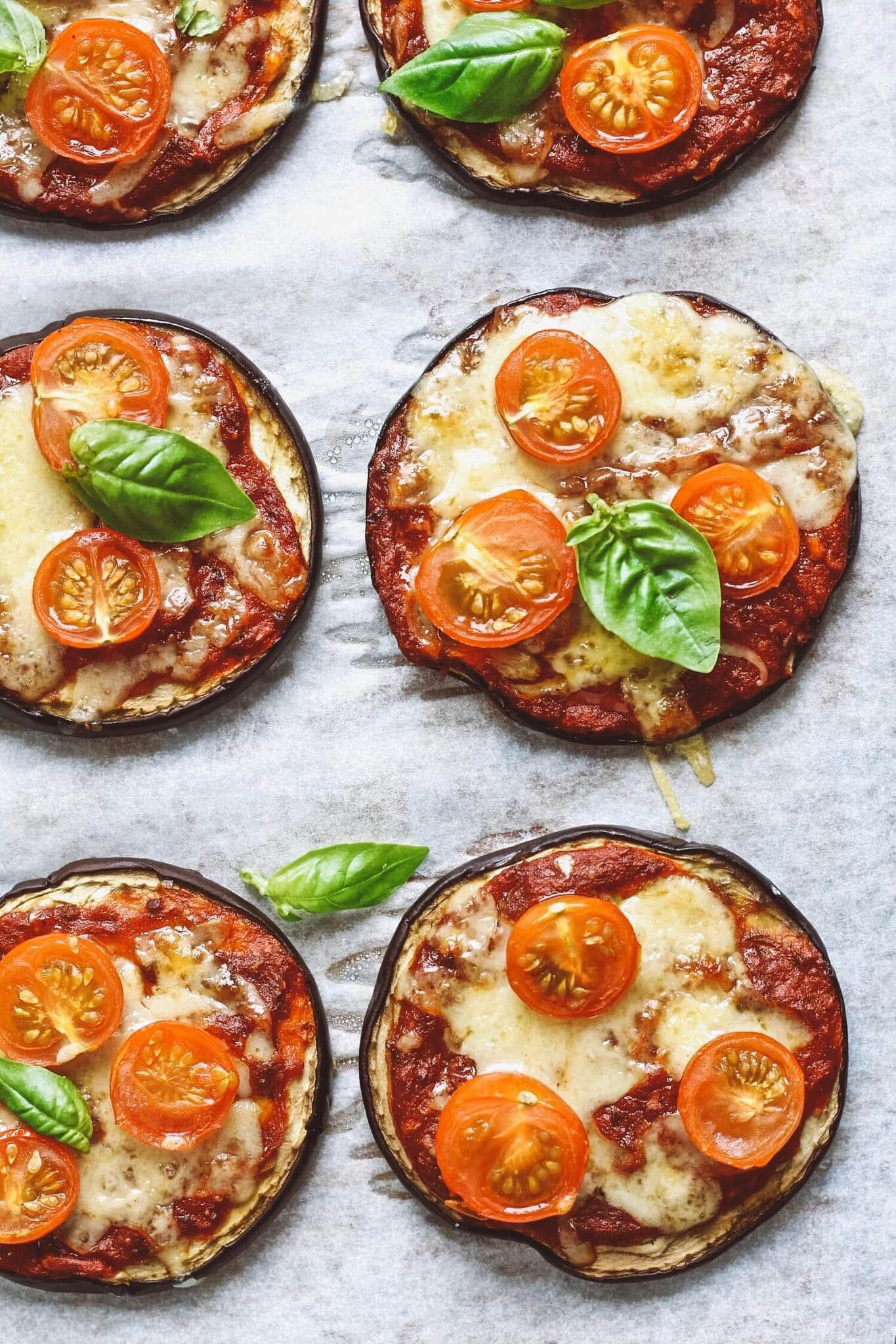 Close up of eggplant pizza topped with pizza sauce, cheese and fresh basil. 