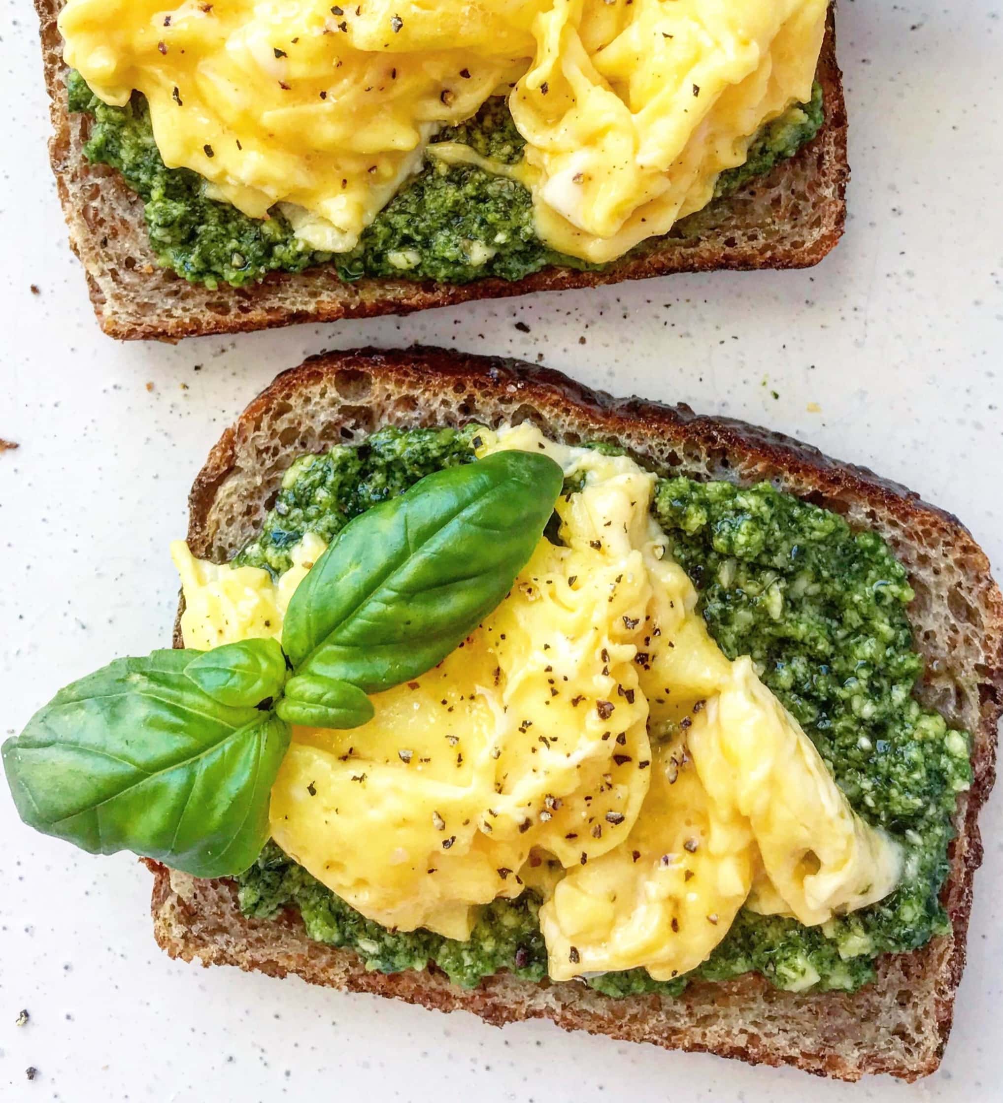 Close up picture of scrambled eggs and pesto on grainy toast.