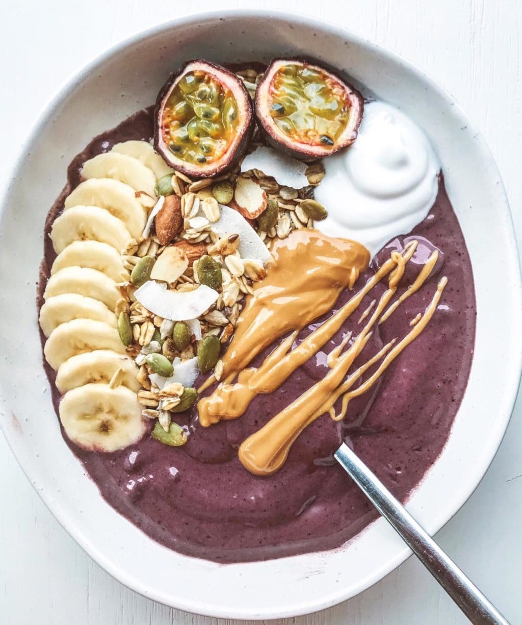 Berry acai bowl topped with banana, muesli and fresh fruit.