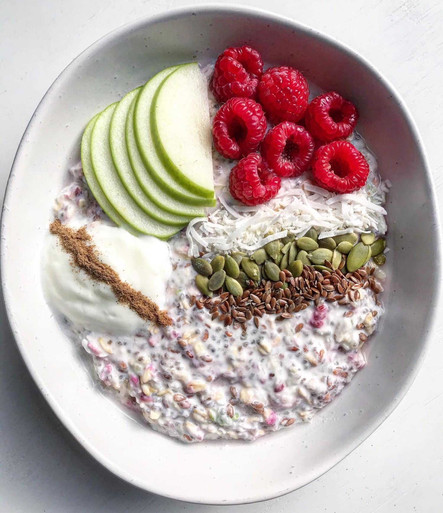 Healthy bircher muesli topped with apple, raspberries and yoghurt.