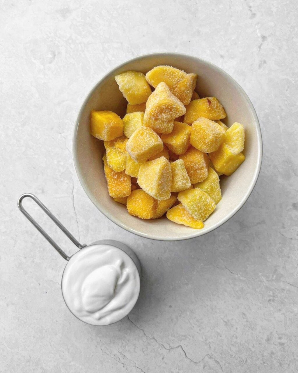 The ingredients needed for mango coconut ice cream including mango and frozen coconut milk