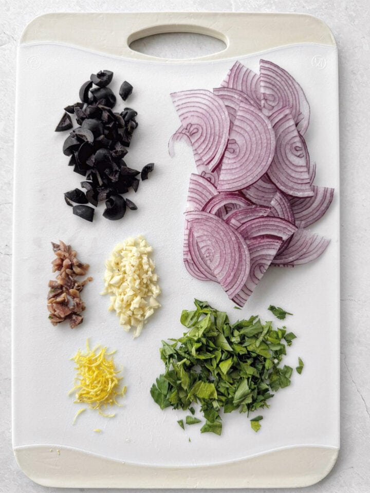 Prepared ingredients on a chopping board for canned tuna pasta