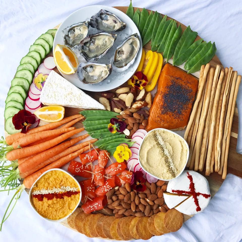 A seafood platter with oysters, smoked salmon,  fresh vegetables, dips, cheese and nuts.