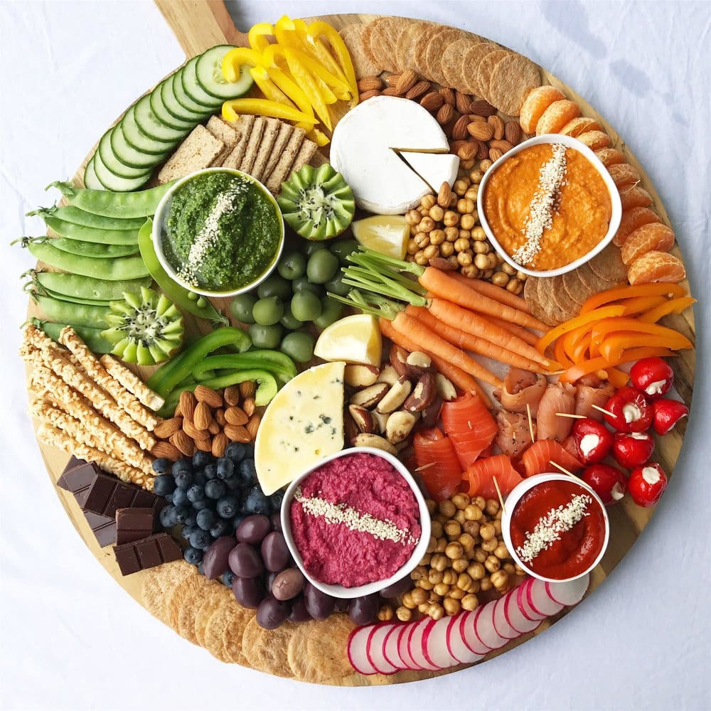 A healthy grazing platter with different dips, crackers, bread sticks, fruit and nuts. 