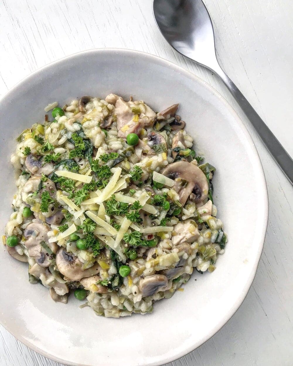 A bowl of chicken and mushroom risotto, garnished with herbs 
