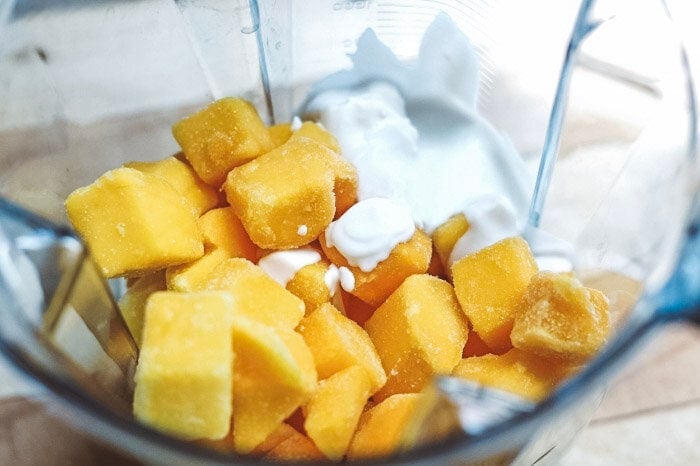 Frozen cubed mango and coconut milk in a blender. 
