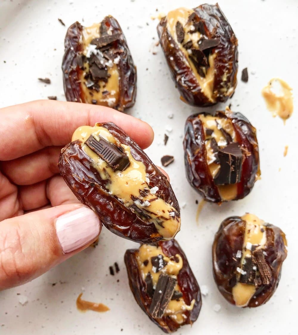 A close up of peanut butter stuffed dates with dark chocolate and sea salt. 