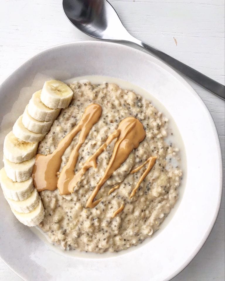 Banana date porridge breakfast topped with sliced banana and a peanut butter drizzle 