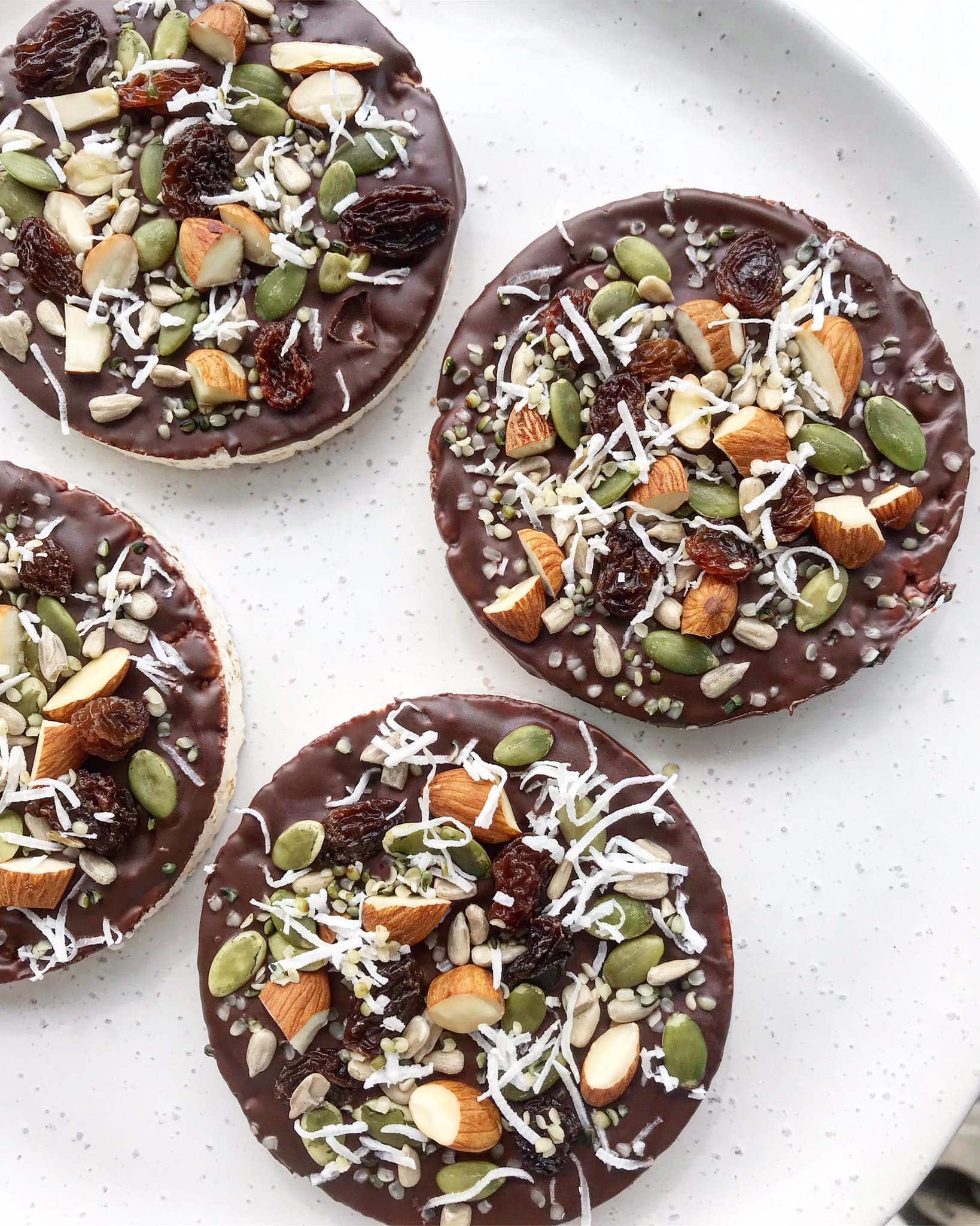 Rice cakes topped with chocolate and sprinkled with a mixture of nuts, seeds, dried fruit and coconut.