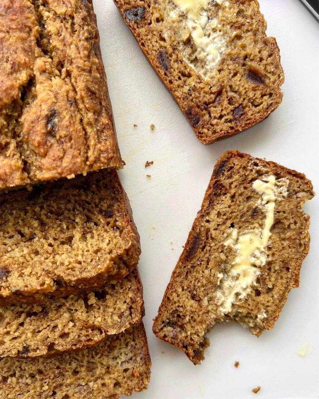 A close up of sliced of banana date loaf slathered with butter.