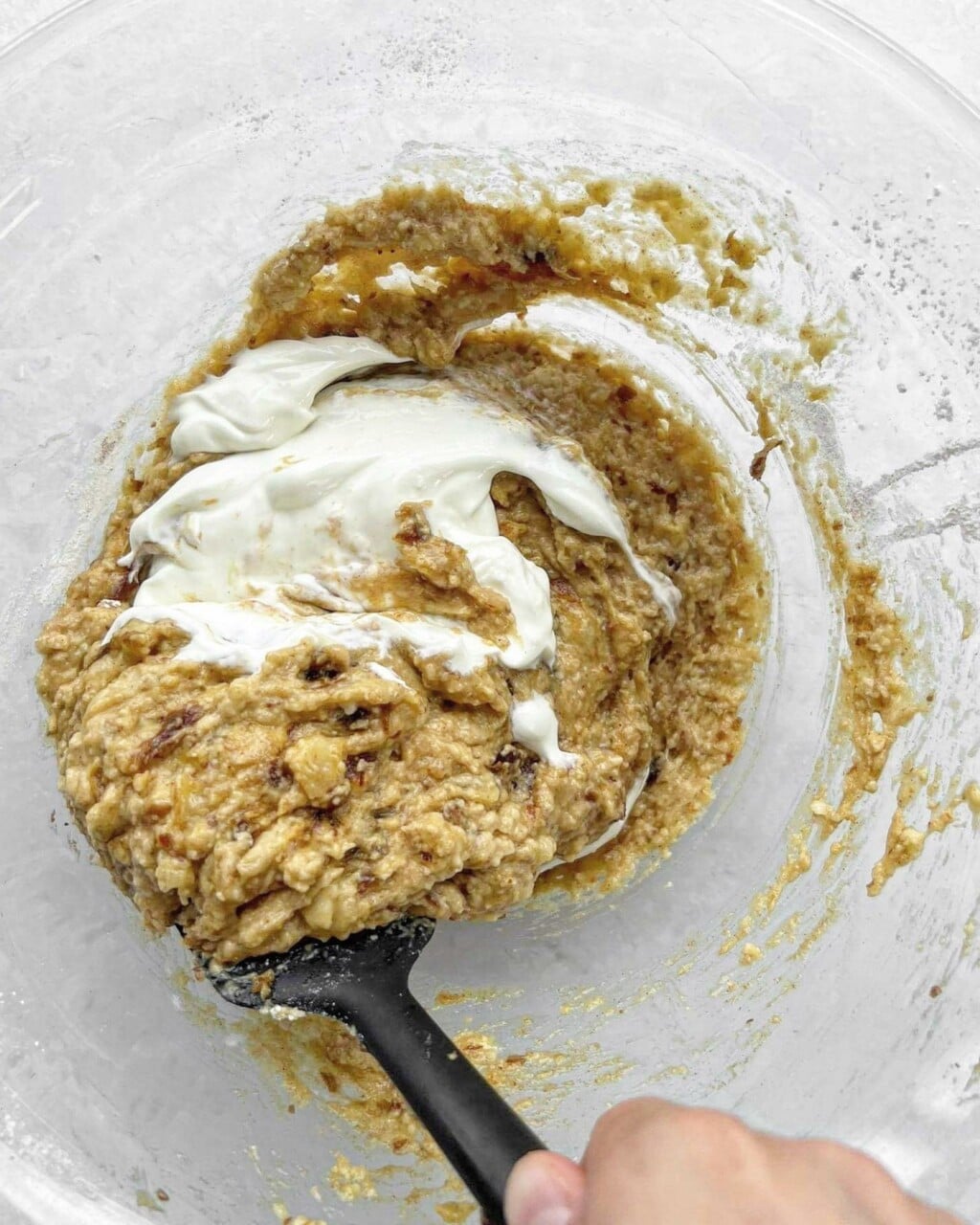 Greek yoghurt being folded into batter using a spatula.