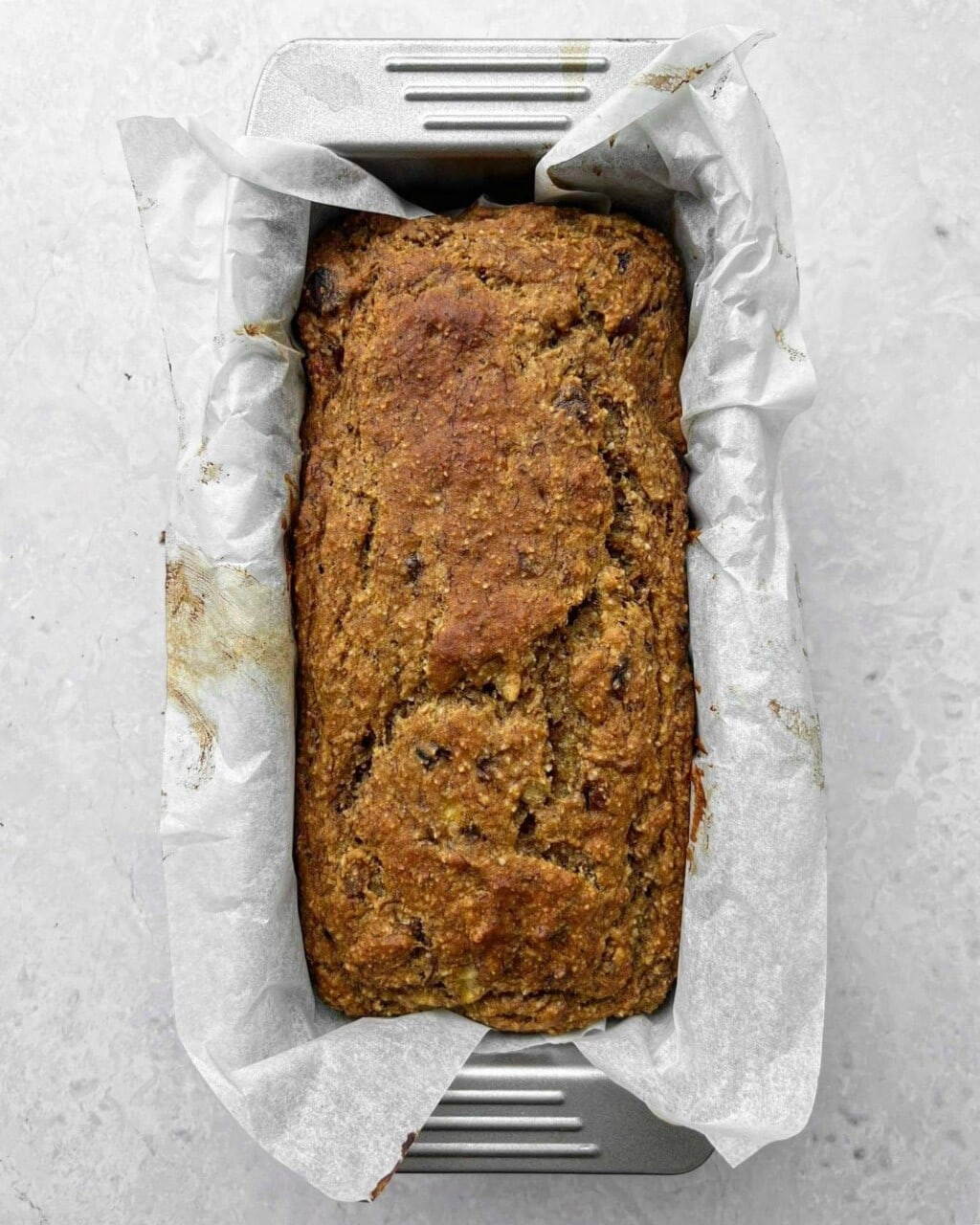 Cooked banana date loaf in a lined loaf tin.