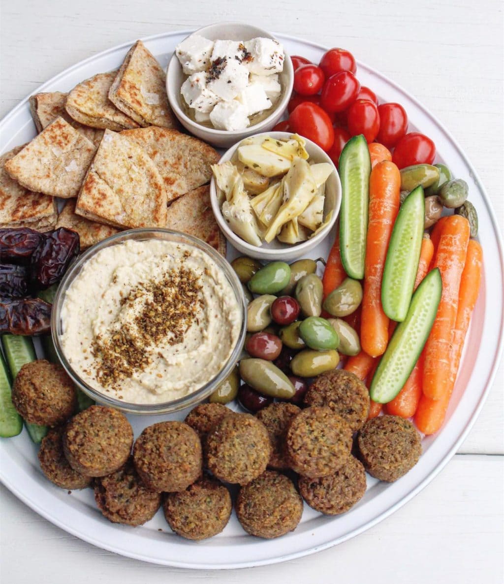 A Mediterranean grazing platter with falafel, olives, vegetable sticks, hummus, pita brea and feta. 