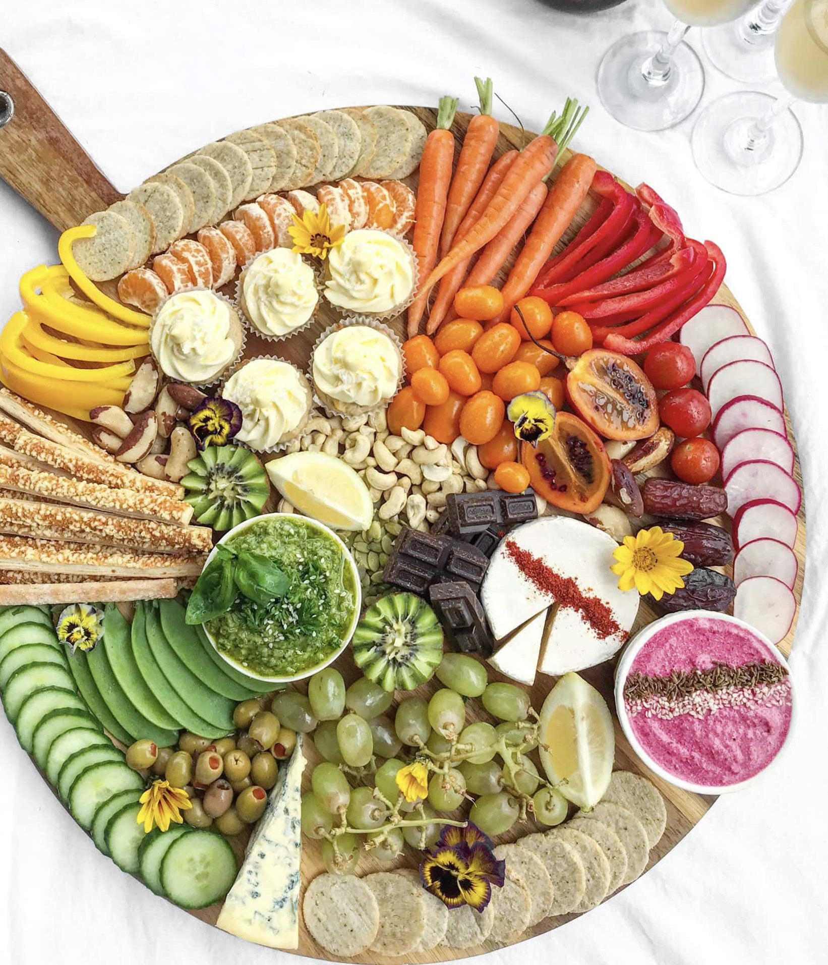 A rainbow-inspired platter with colourful dips, fruit, vegetables, nuts and crackers.