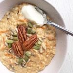 A picture of a bowl of carrot cake porridge topped with pecans, seeds and yoghurt.
