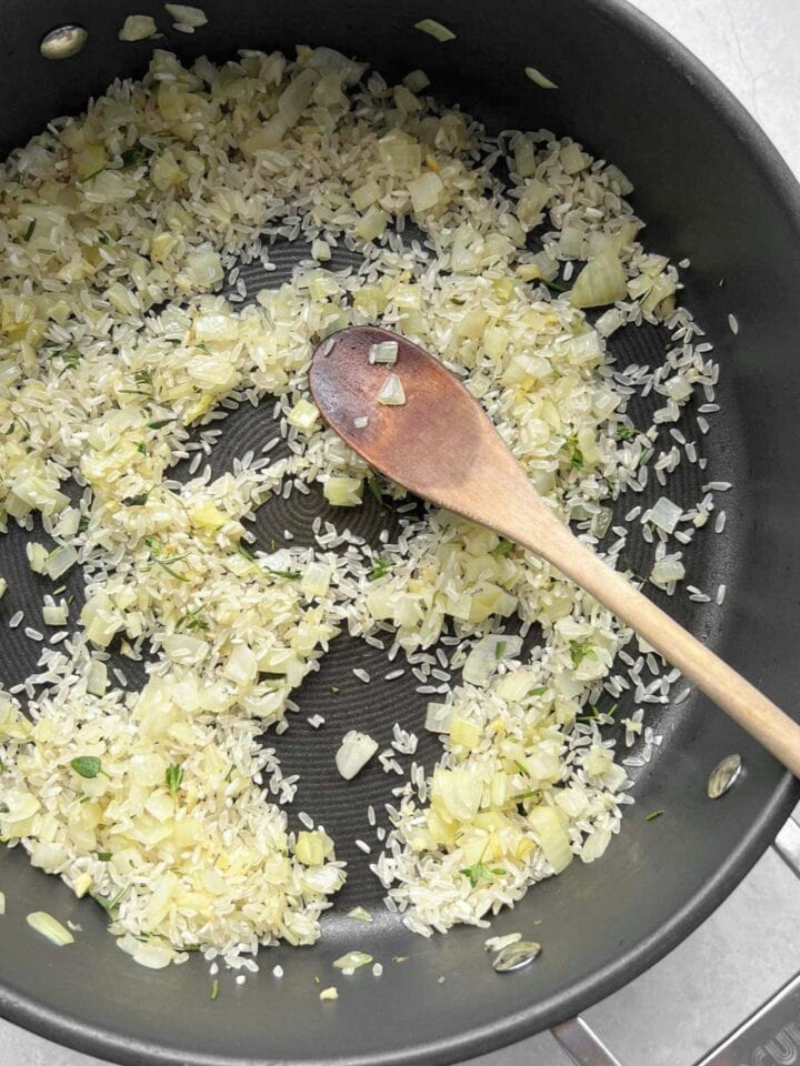 Risotto rice and herbs in a frypan.
