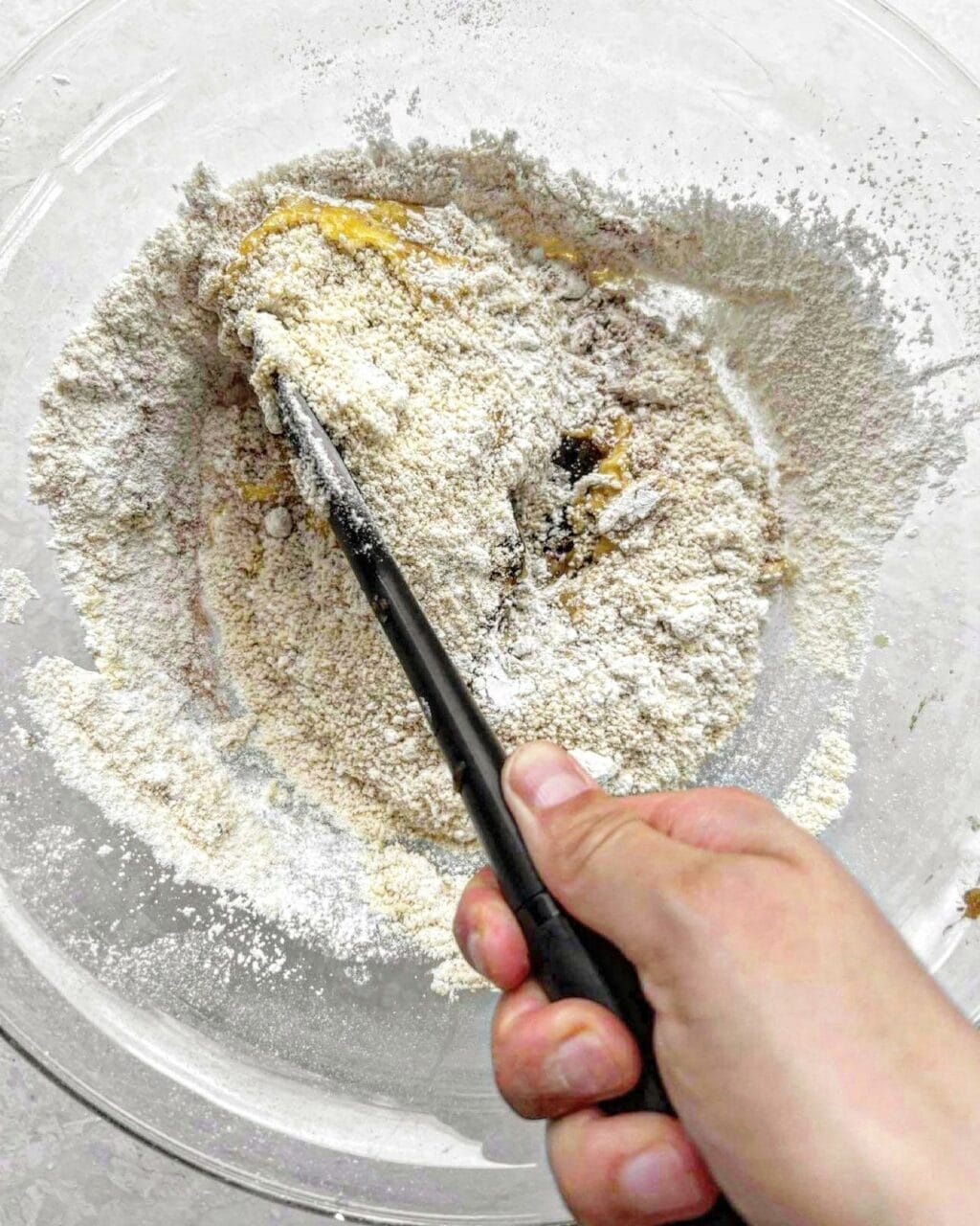 Flour, baking powder and soda, cinnamon and date paste being folded together.