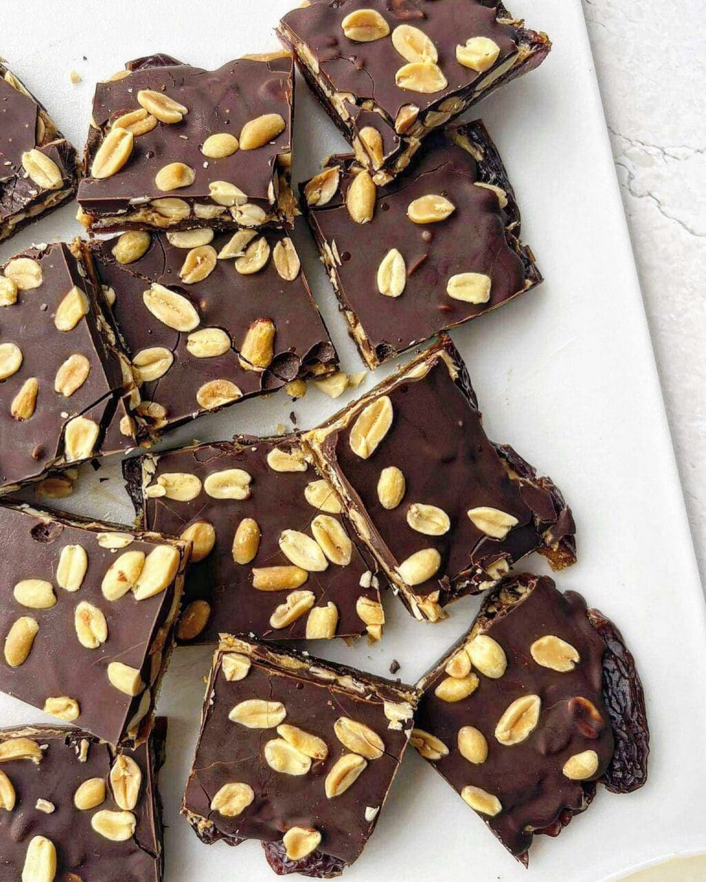 Squares of chocolate date bark topped with roasted salted peanuts.