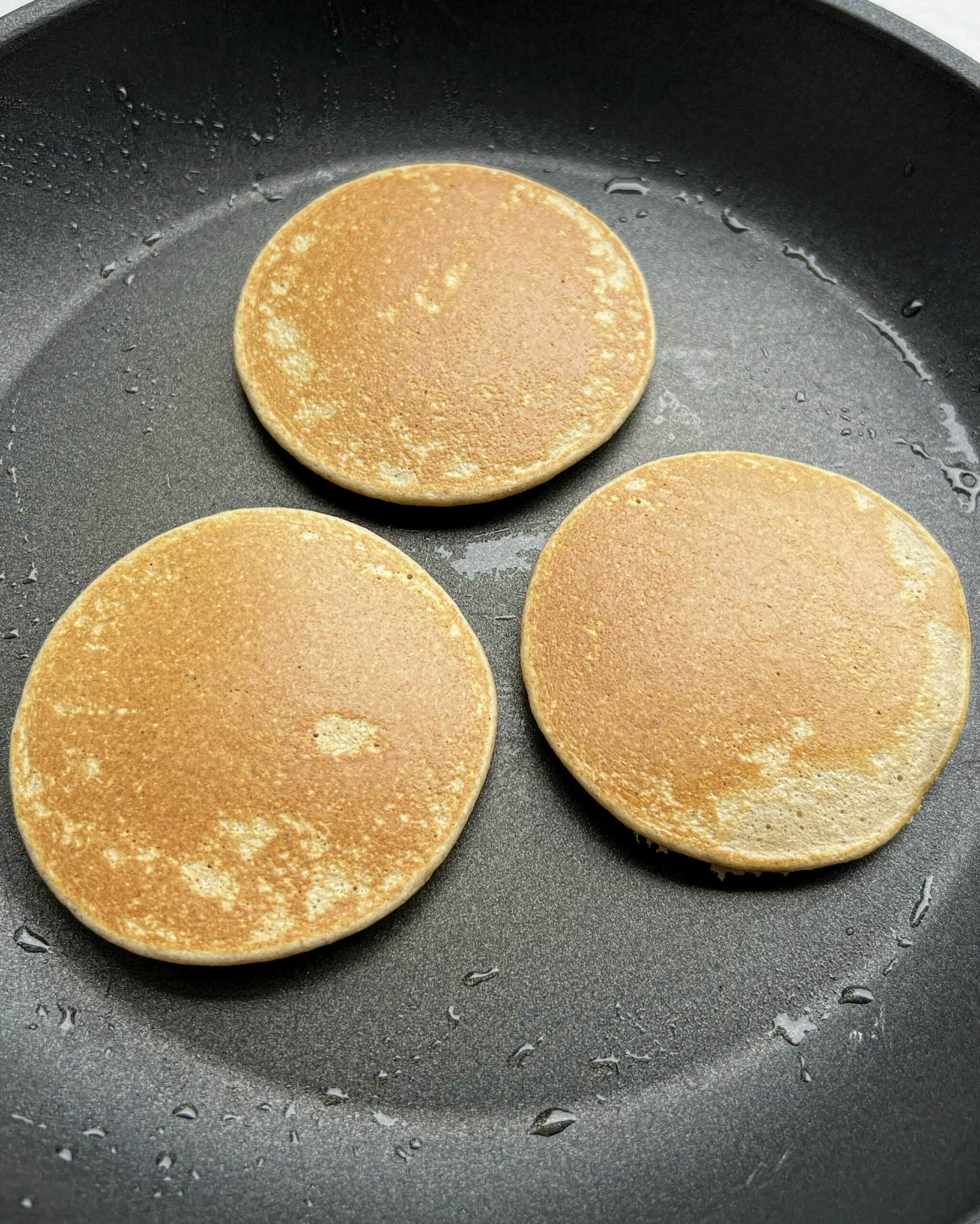 Cooked banana oat pancakes in a fry pan