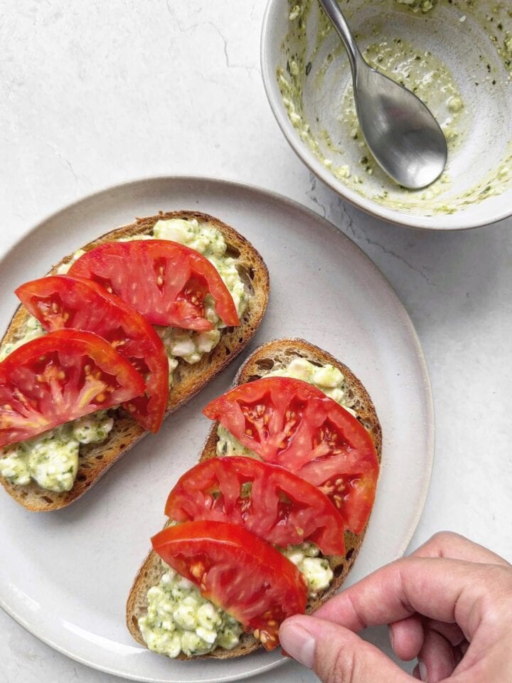 Topping cottage cheese toast with sliced tomatoes.